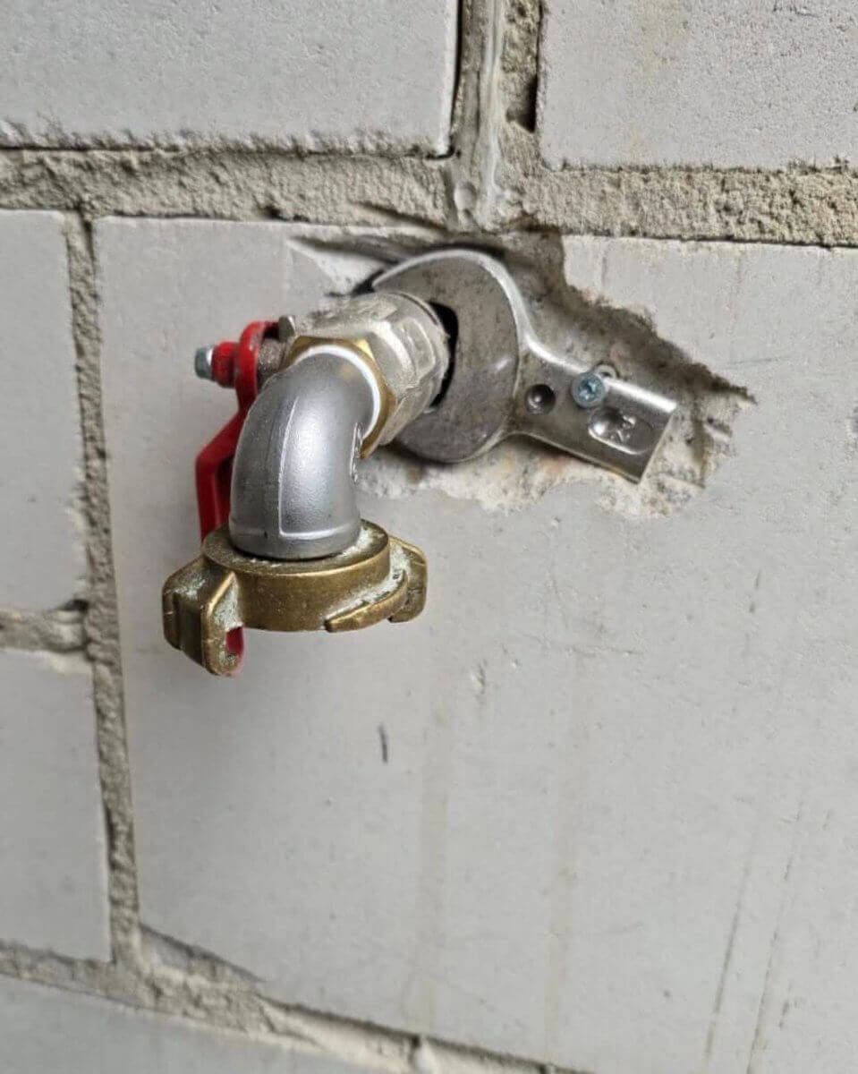 Wasseranschluss mit Armatur an einer Backsteinwand