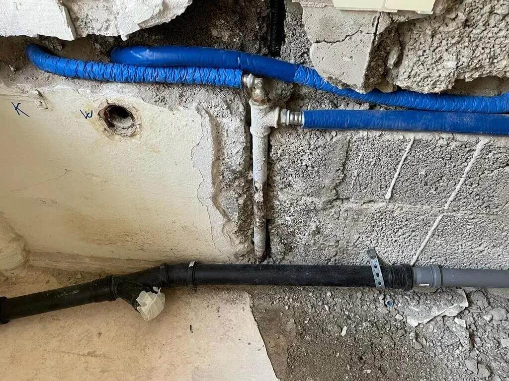 Wandschlitz mit Wasserleitungen und blauen Elektrorohren